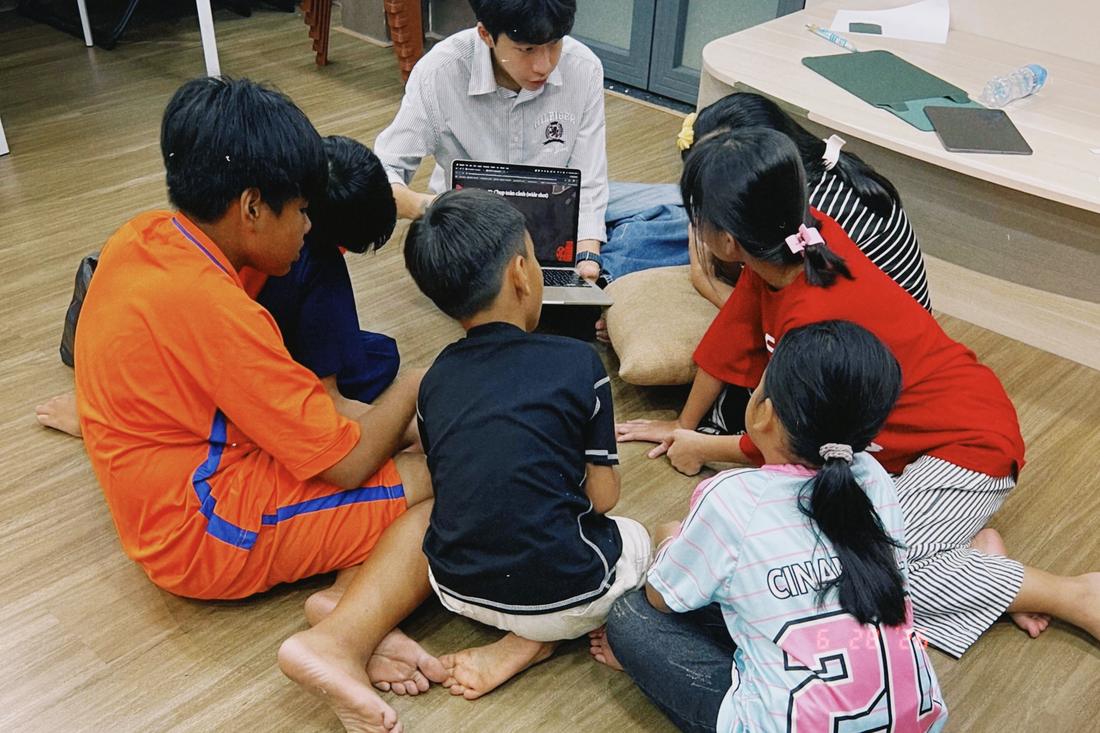 A Chạm volunteer showing a group of children camera shots on a laptop during the film class.